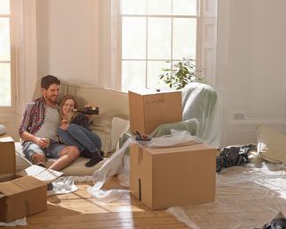 couple sat in living room surrounded by moving boxes