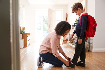 Clarks Sale: Single Mother At Home Getting Son Wearing Uniform Ready For First Day Of School