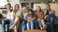 A multigenerational family sit on a couch together.