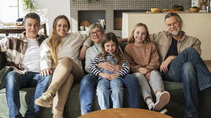 A multigenerational family sit on a couch together.