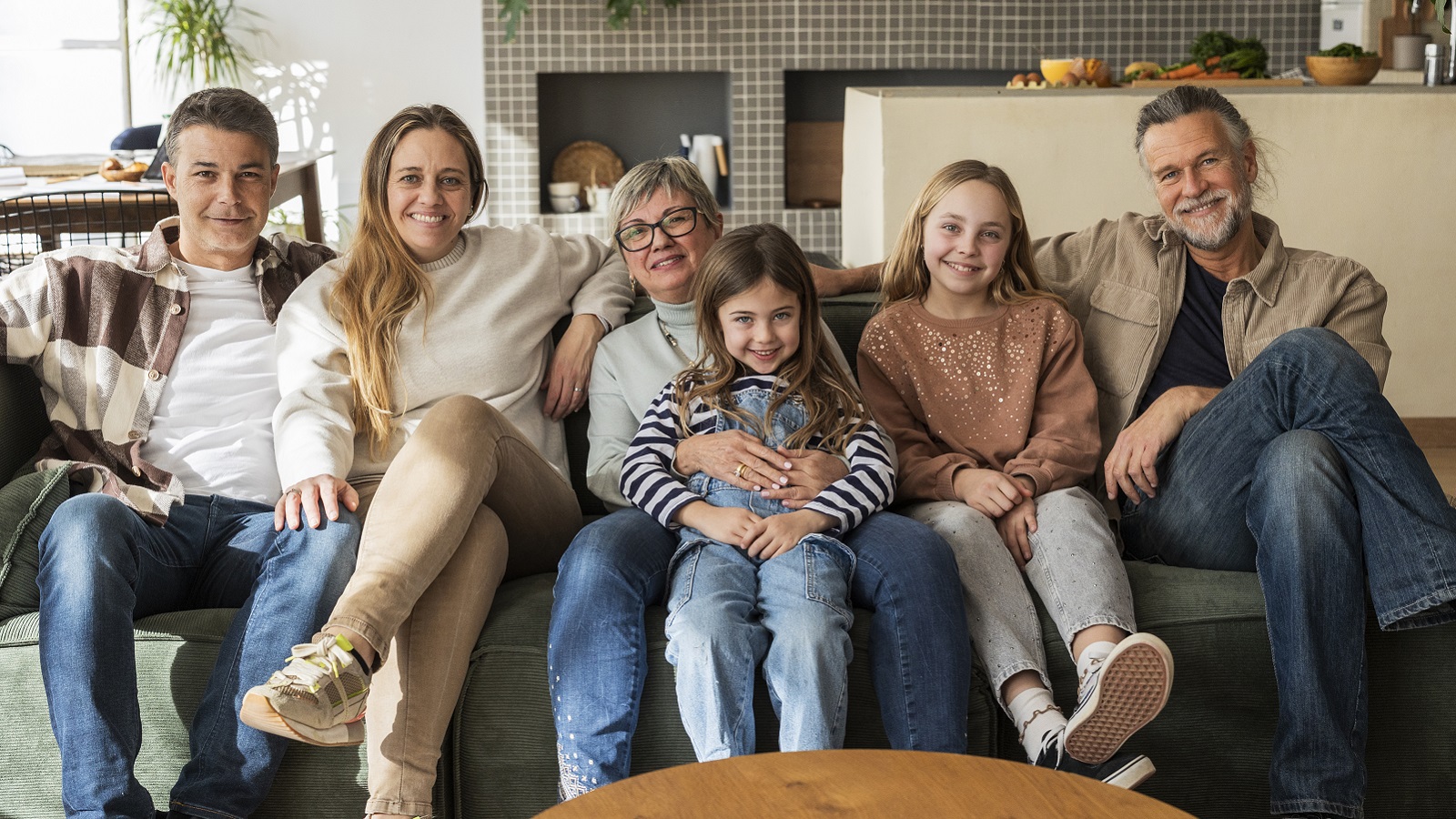 A multigenerational family sit on a couch together.