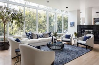A living room with blue traditional rug and white sofas and chairs