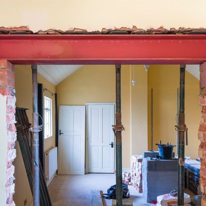 Knocking down walls during a renovation project, with acrow props supporting the RSJ as it's installed