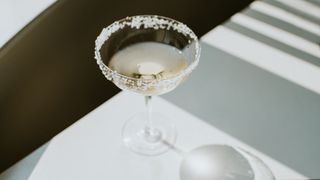 Margarita drink in coupe glass with salt around the rim on white marble table