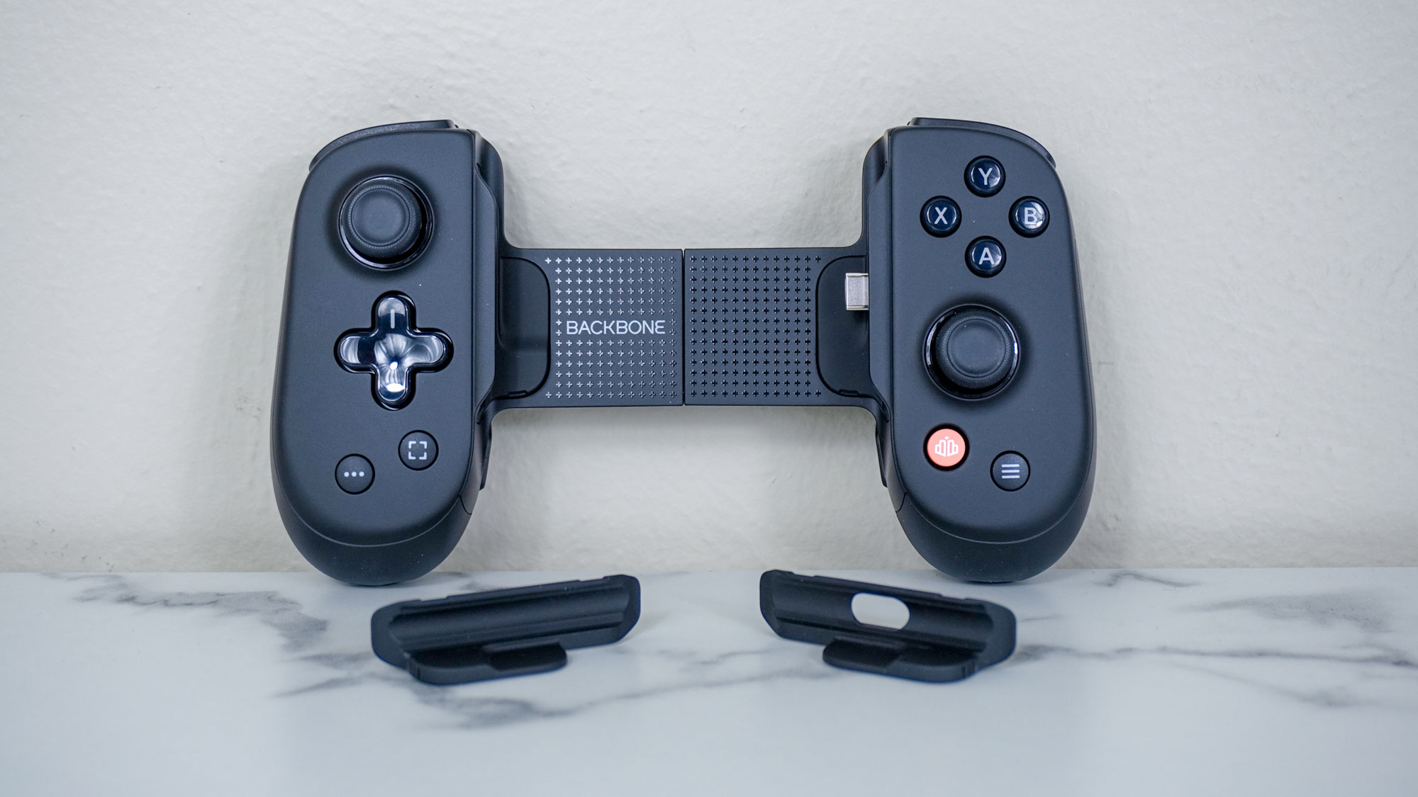 The Backbone Pro controller unboxed on a table with the extra plastic inserts it ships with