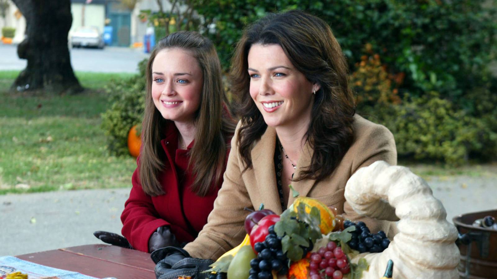 Rory and Lorelai Gilmore sitting at a picnic table in coats