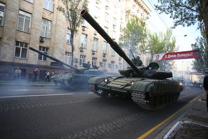 People walk past the tanks of pro-Russian separatist forces during a rehearsal of Victory Day parade in the center of Donetsk on May 3, 2017. 