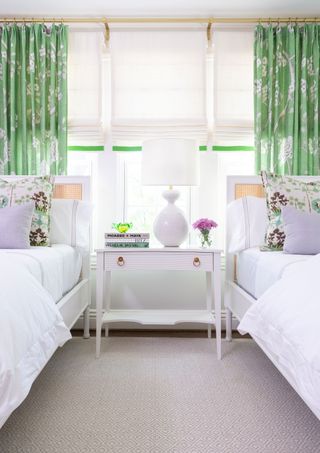 green and lavender fabrics in twin bedroom with roman shades and floral patterned pillows