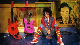Earl Slick sits on the set of SNL beside two Day-glo S-styles