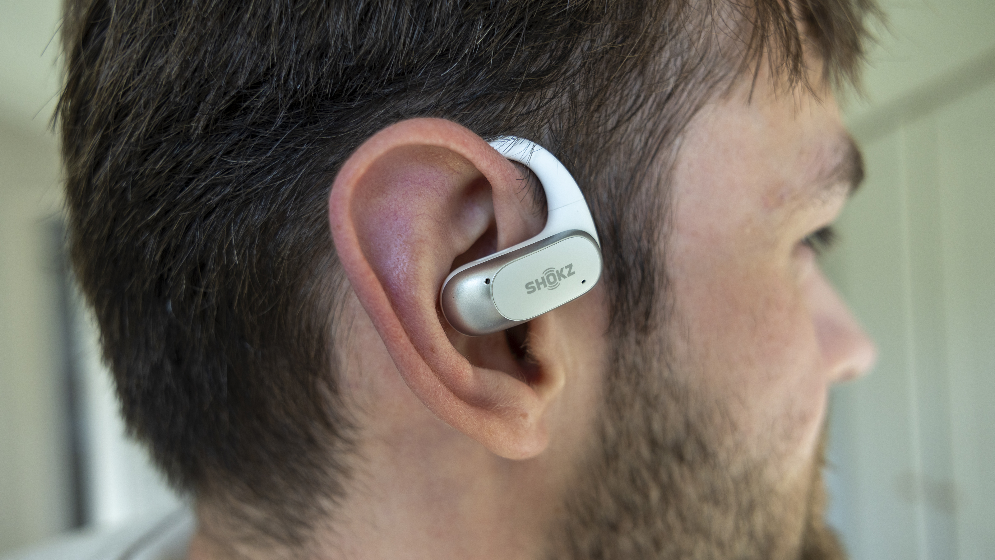 A side view of a male wearing the Shokz OpenFit Air headphones