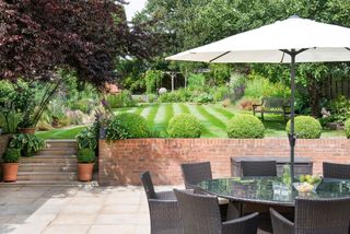 garden with a large patio and dining area, with a lawn on a different level