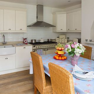 kitchen diner area with cream painted units range cooker and wicker chairs
