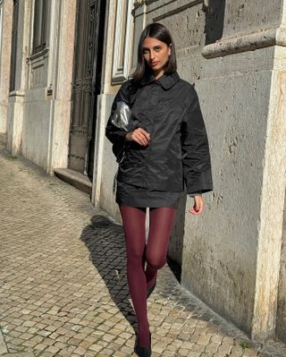 Fashion influencer @salome.mory wearing a chic winter outfit styled with 2024/2025's burgundy tights trend.