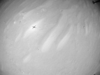 A photograph from Ingenuity's 12th flight, conducted on Aug. 16, 2021, shows the silhouette of the helicopter on the rippled surface of Mars.
