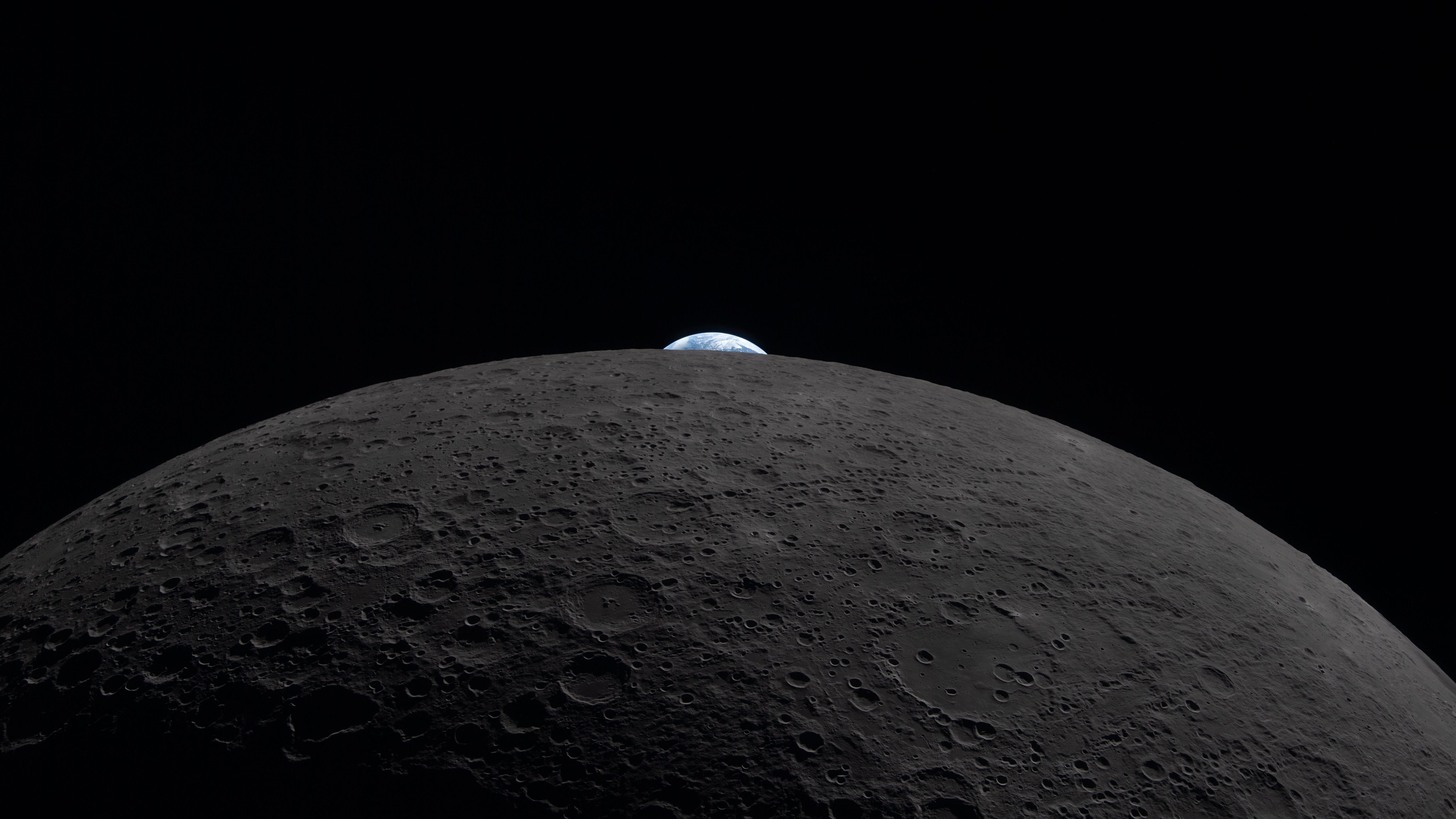 A tiny Earth rises over the surface of the Moon, as seen from Artemis II