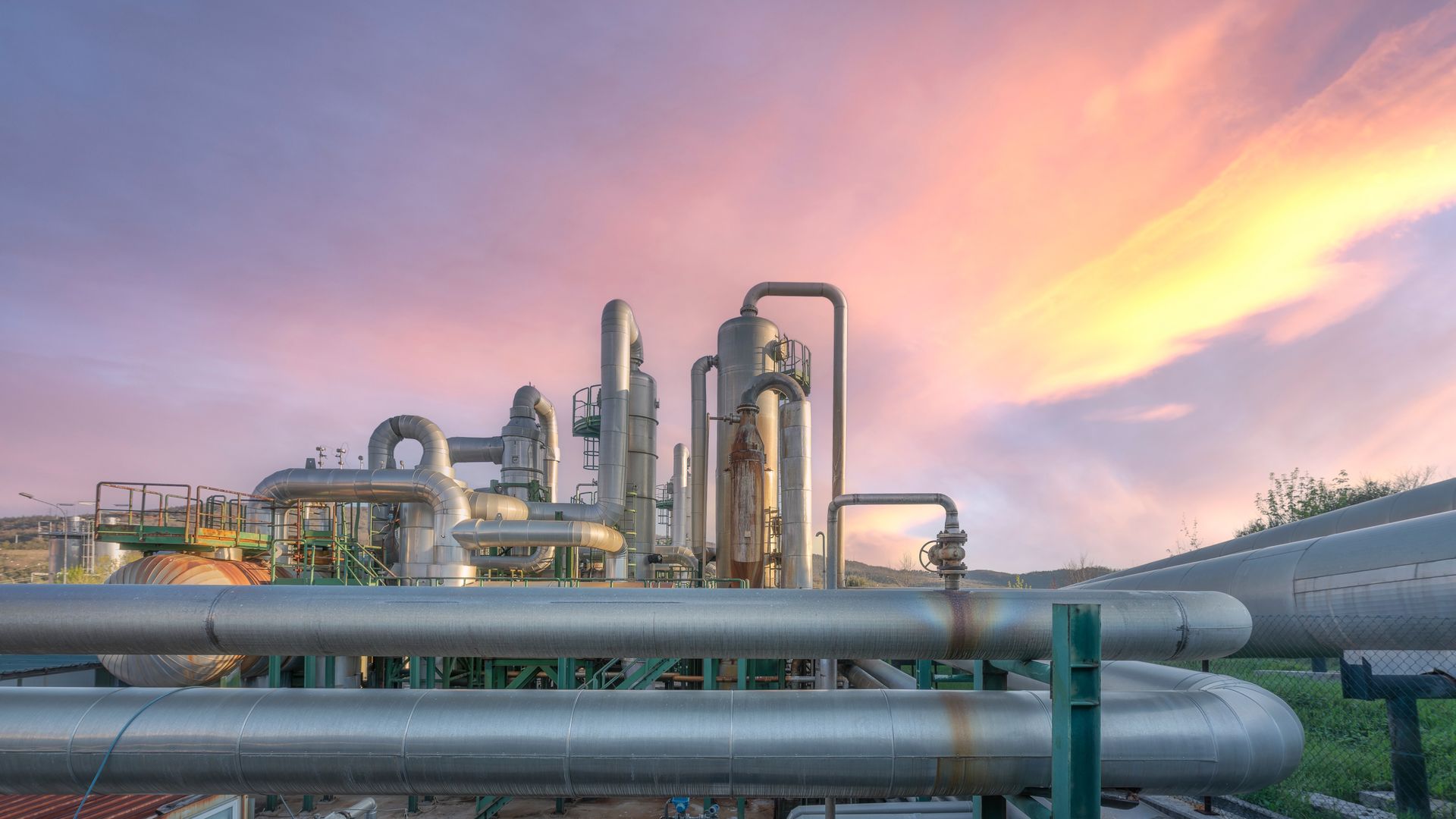 Industrial geothermal power plant pipelines at sunset in Larderello, Tuscany region. Steam pipes and equipment for renewable energy production with dramatic pin