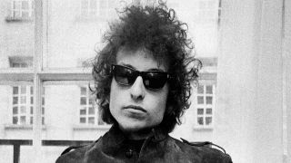 Bob Dylan posing for a photograph in sunglasses in 1966