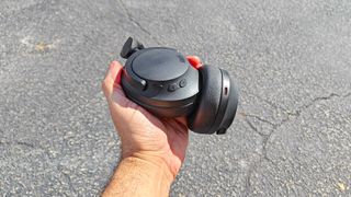 1More SonoFlow SE paced in an outstreched hand showing earcups with control button