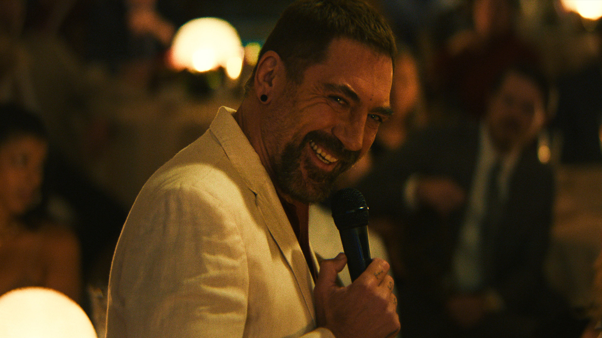 Javier Bardem grins while holding a microphone as Max Cady in Apple TV's Cape Fear remake