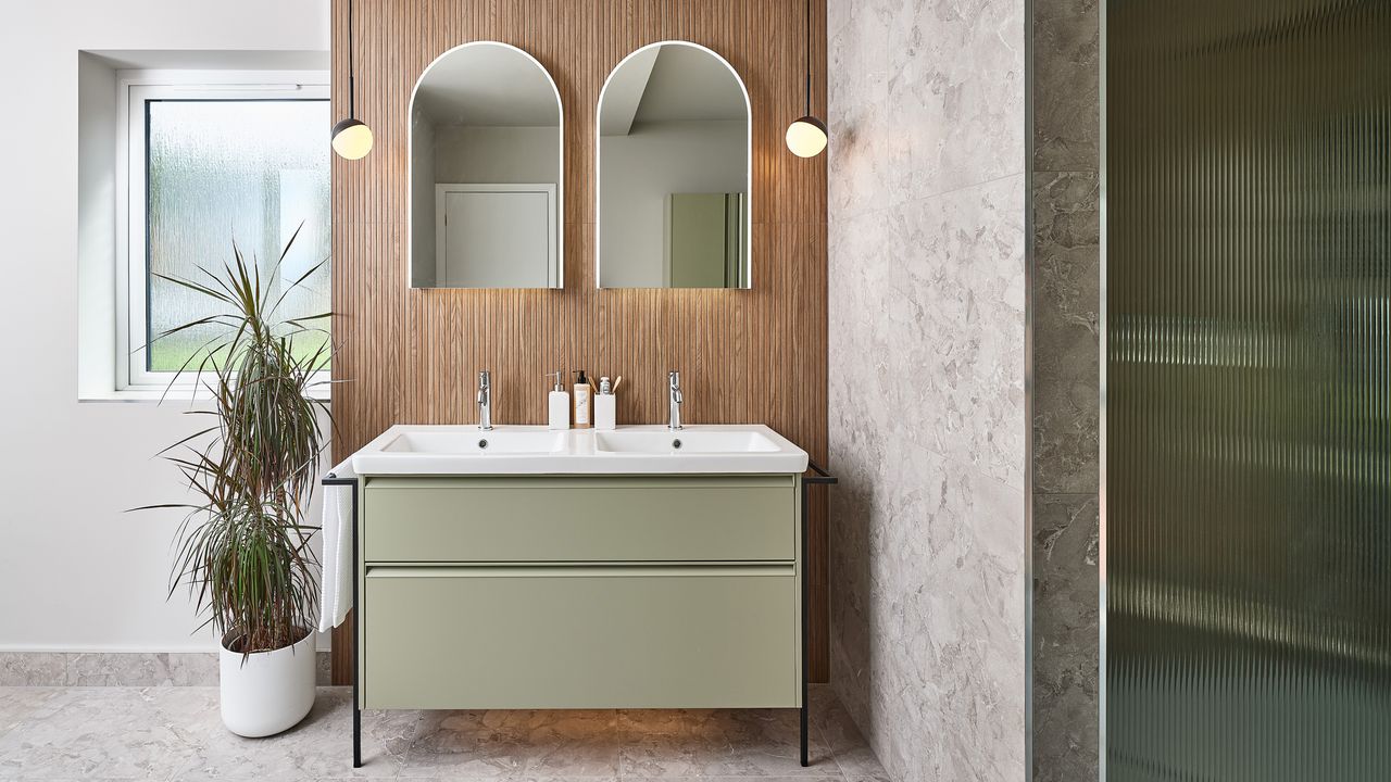 a double basin vanity unit with double mirrors and ceiling hung pendant lights