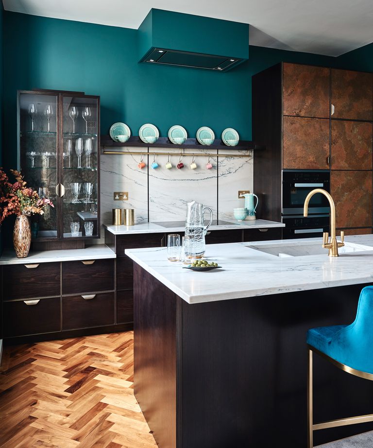 Kitchen trends 2021 showing dark cabinets with herringbone flooring and a decorative display cabinet for glasses