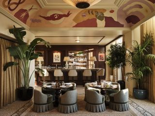 A swanky salon features ceiling murals, fringed upholstered chairs, and a old glamour style vibe.