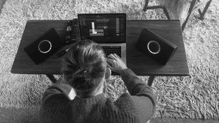 AIAIAI UNIT-4 speakers on desk as man sits at laptop