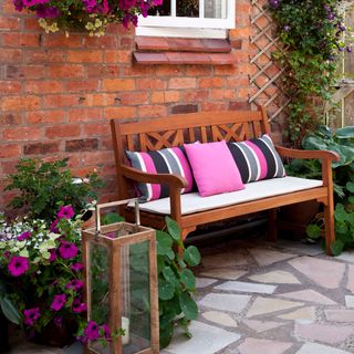 courtyard garden with wooden bench and pink cushions