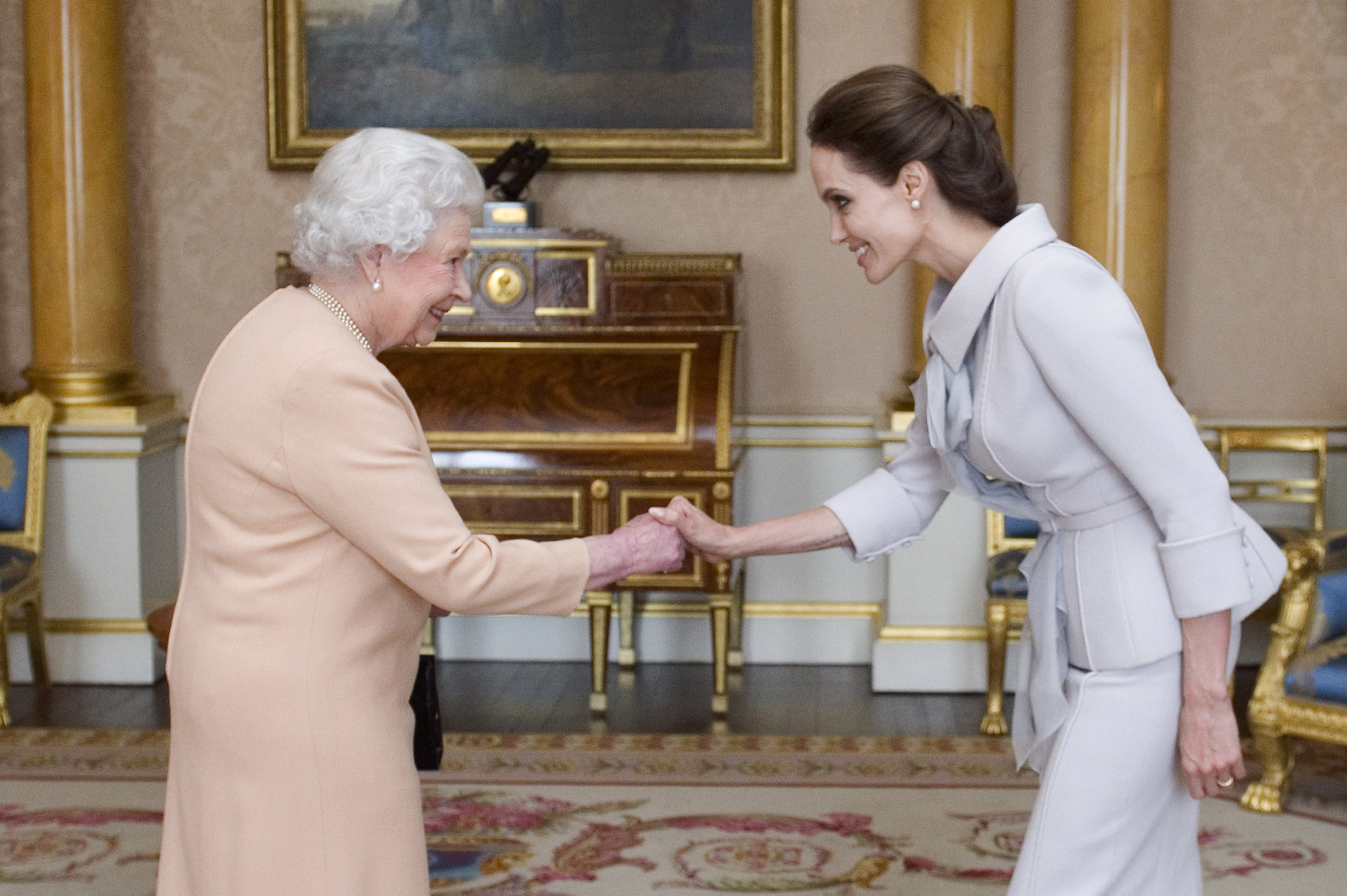 Actress Angelina Jolie is presented with the Insignia of an Honorary Dame Grand Cross of the Most Distinguished Order of St Michael and St George by Queen Elizabeth II in the 1844 Room on October 10, 2014 at Buckingham Palace, London.