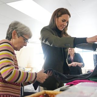 Princess Kate foldling clothes at a charity shop next to a woman