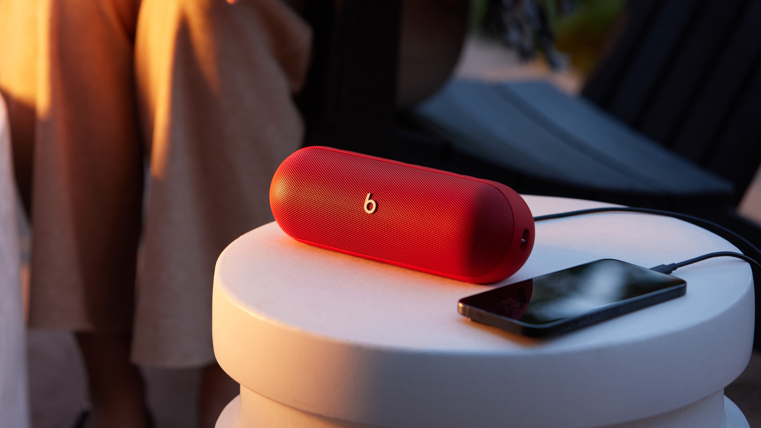 Beats Pill в Statement Red на столе с проводным аудиоразъемом USB-C для смартфона