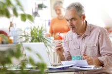 Older couple at home, man with laptop - stock photo
