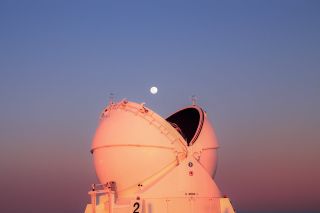 an open observatory building appears as an open mouth facing upward, beneath a bright full moon.