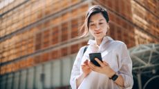 Woman looking at her phone standing outside of an office building