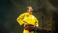 a man with curly, long hair sings into a microphone