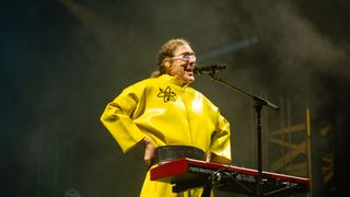 a man with curly, long hair sings into a microphone