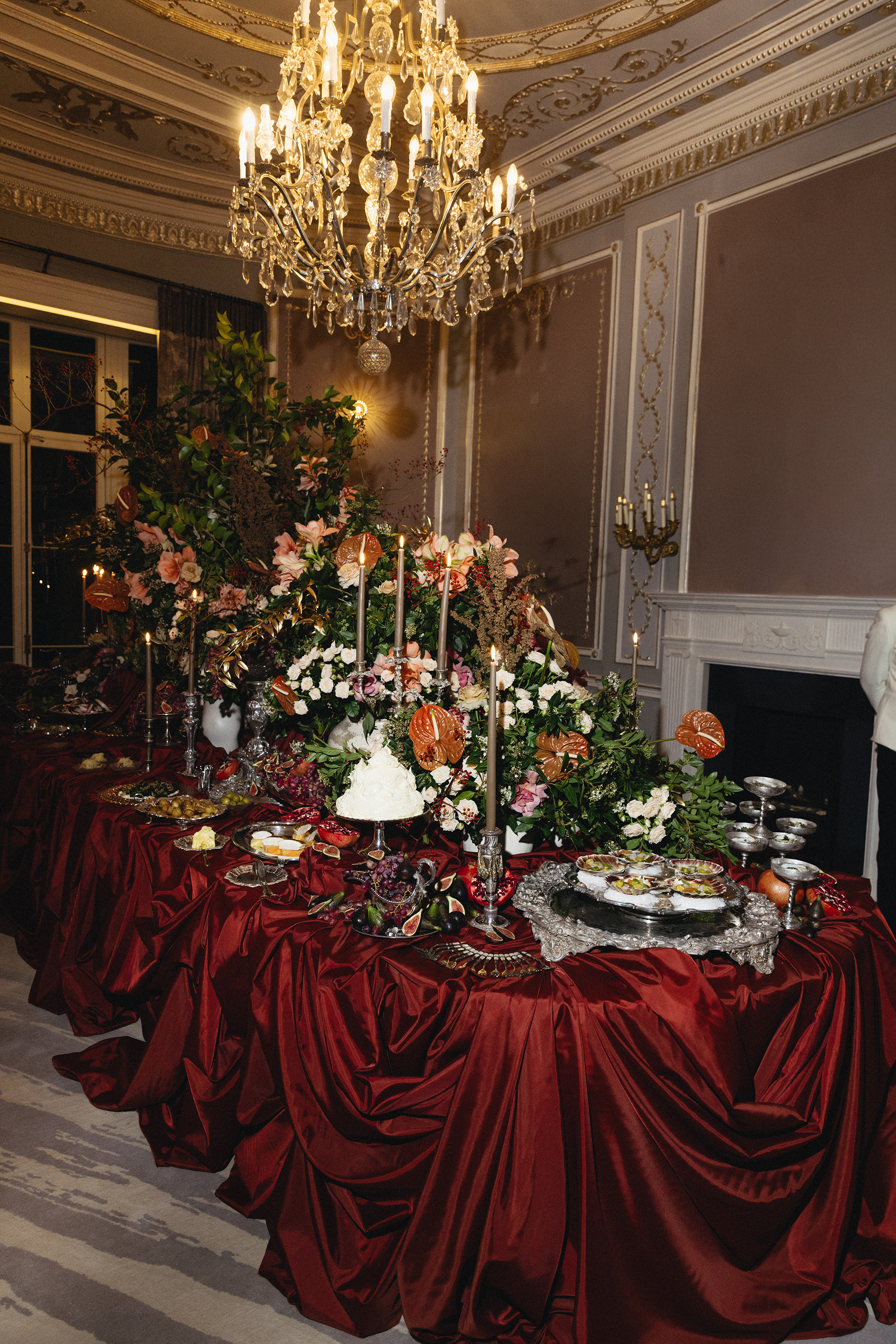 a feasting table with dramatic red draped table cloth and chandelier