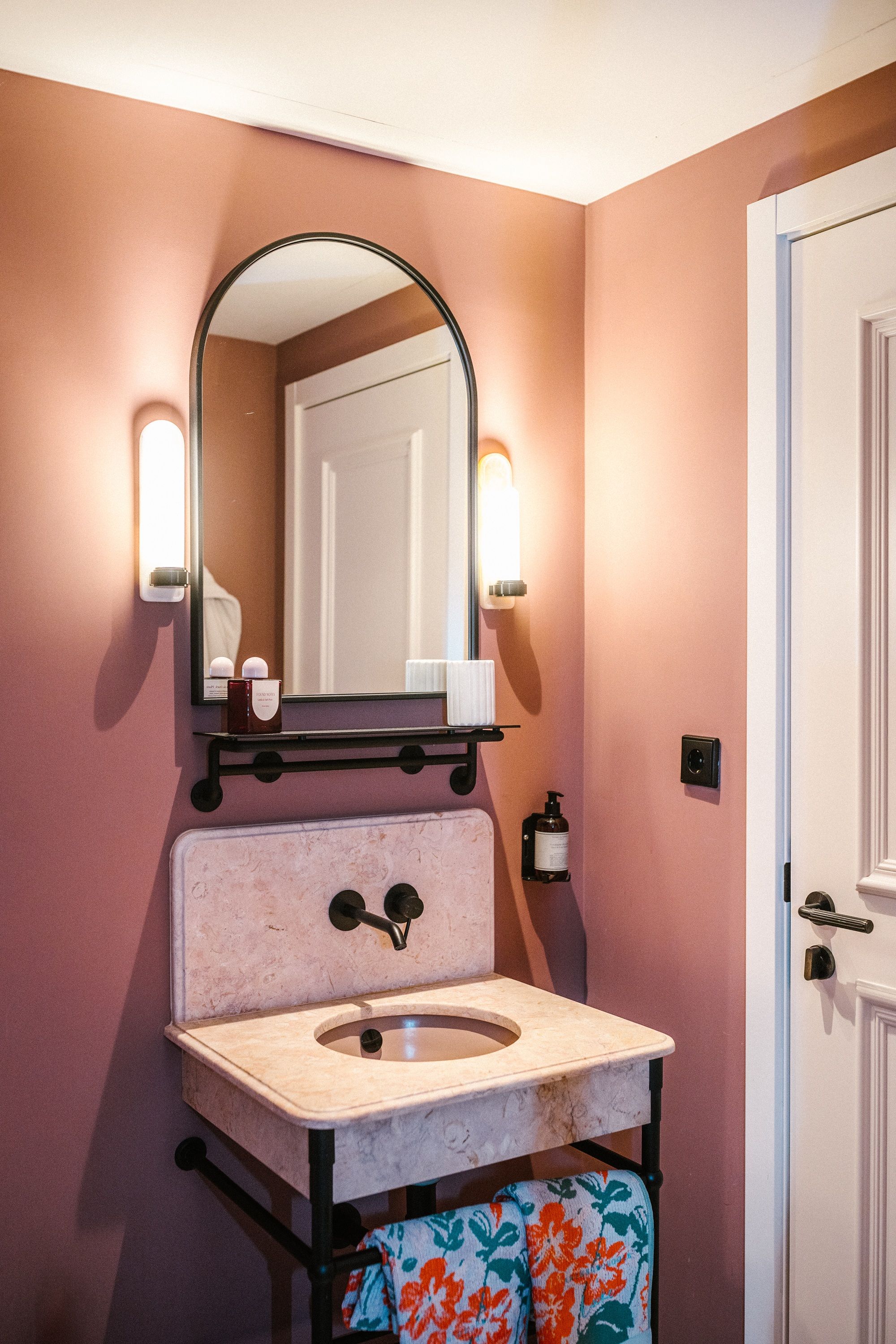 a terracotta bathroom with stone vanity and patterned towels