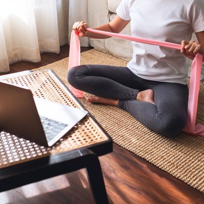 A woman doing a Pilates band workout at home