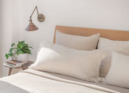 A bedroom with beige and pale pink pillows on the bed