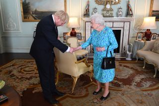 Queen Elizabeth wearing a blue dress shaking Boris Johnson's hand inside Buckingham Palace