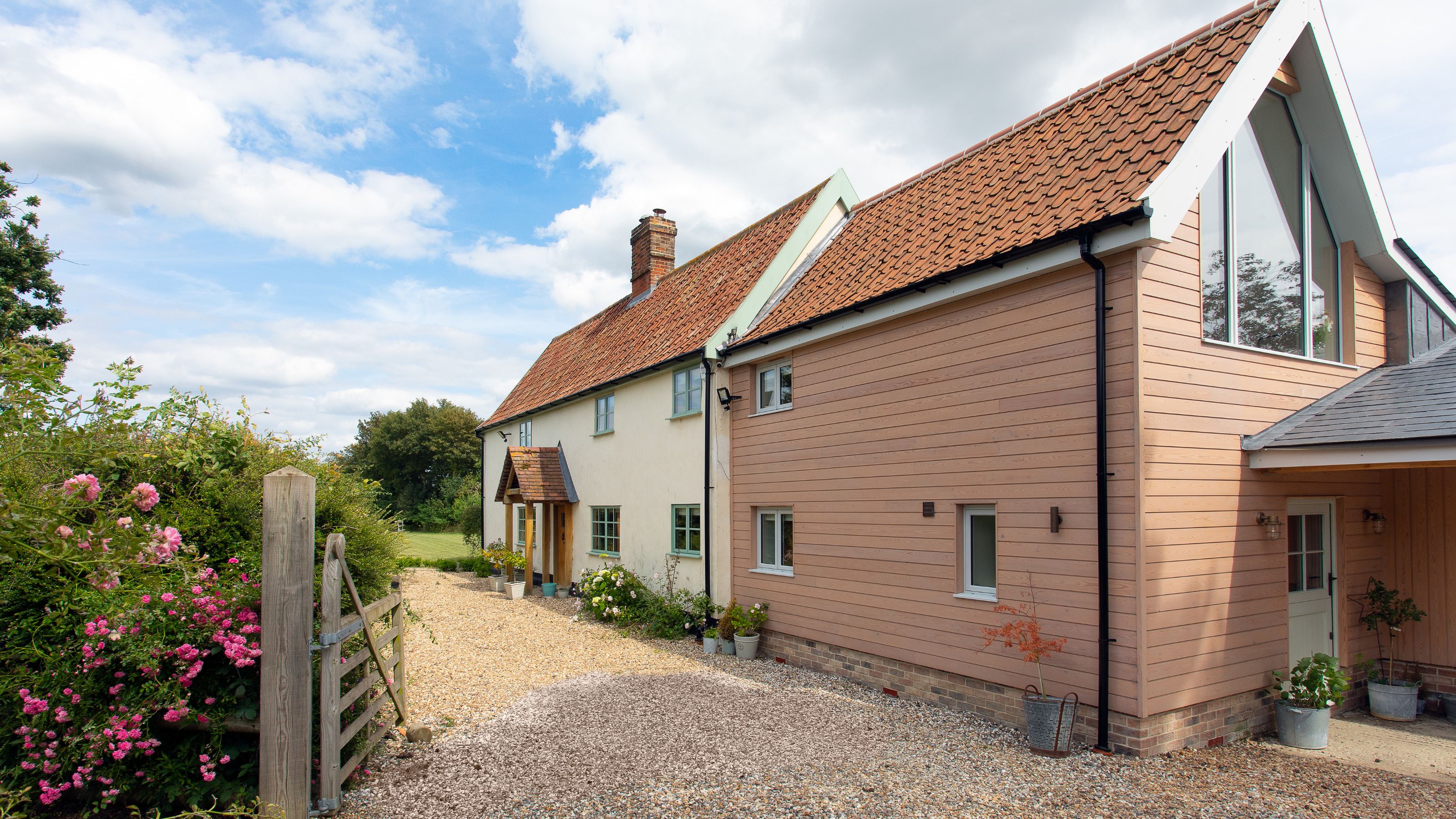 Gravel driveway in front of cottage style home with cladding and a porch