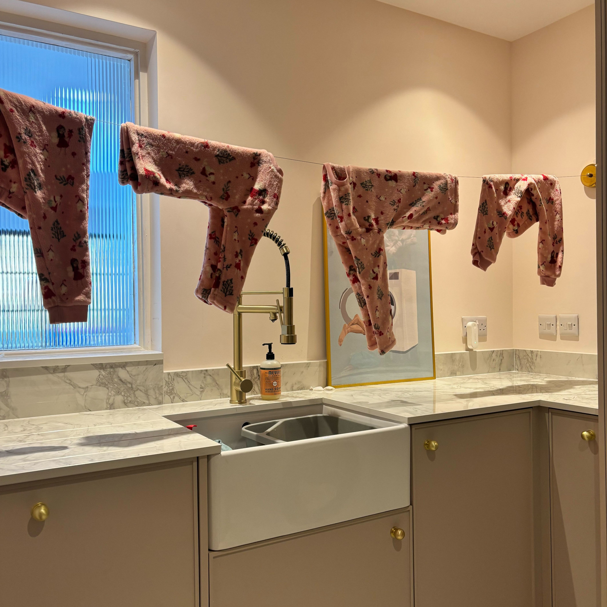 brass retractable clothes line with pyjamas on it in a laundry room