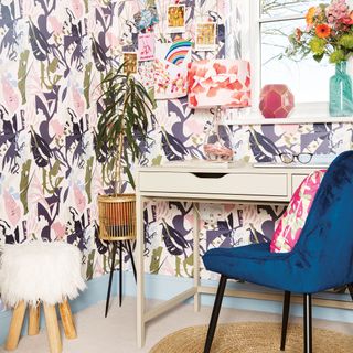 Home office with botanical wallpaper, metal desk, blue velvet chair and houseplant