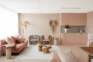 A pink studio apartment showing a pink sofa, pink walls and pink kitchenette