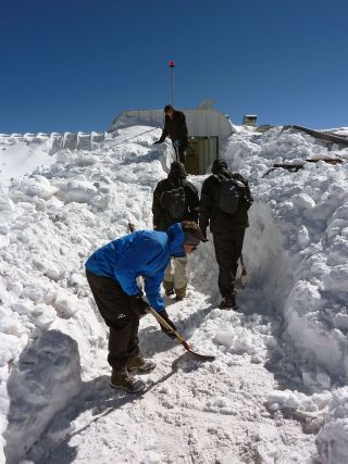 The ArTeMiS space camera team shovel snow to get into the APEX control building on the Chajnantor Plateau in northern Chile. In the foreground is Laurent Clerc, in the middle are Jérôme Martignac (left) and François Visticot (right), and in the background by the door to the building is Yannick Le Pennec.