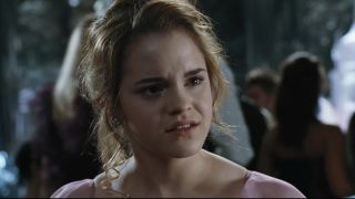 Emma Watson sits in a pink dress with a look of disgust in Harry Potter and the Goblet of Fire.