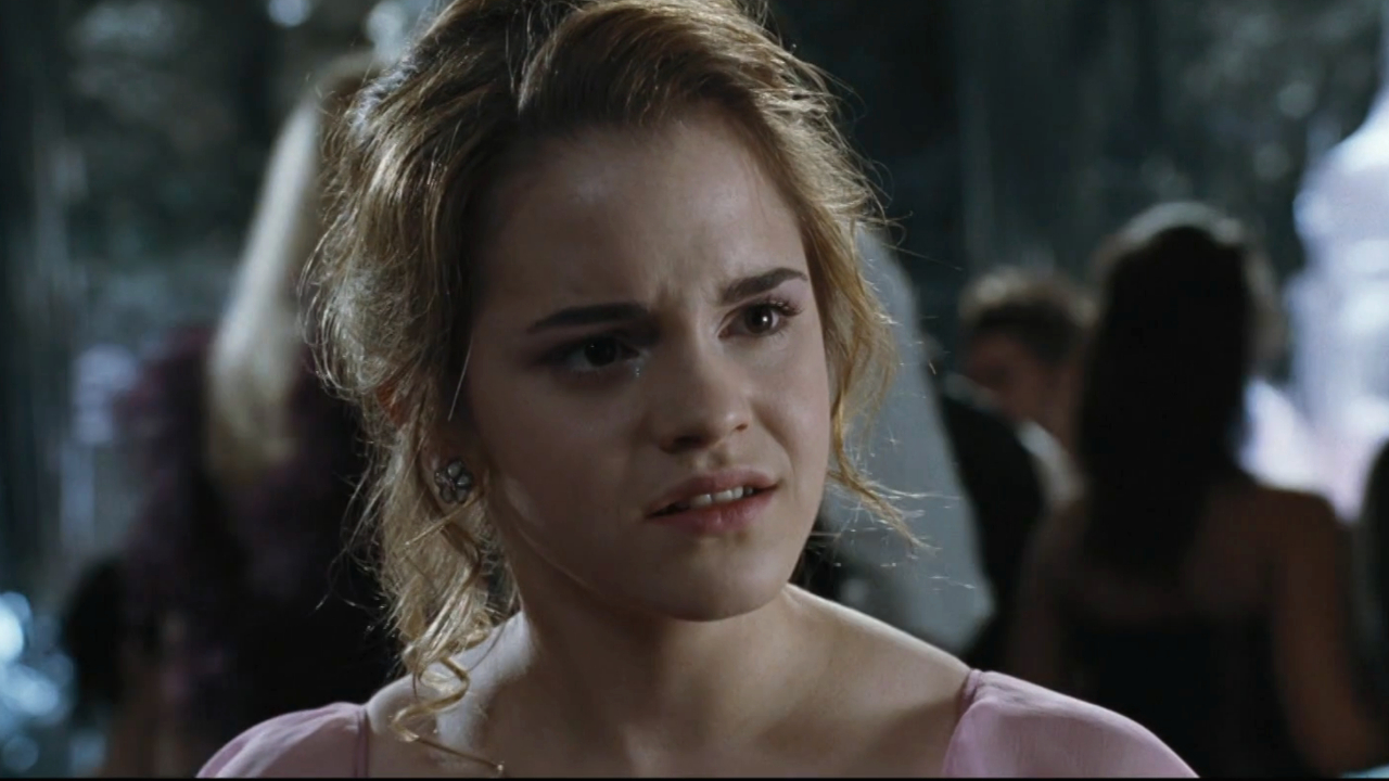 Emma Watson está sentada con un vestido rosa y una mirada de disgusto en Harry Potter y el cáliz de fuego.