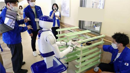 A D1 wheeled humanoid robot carries dishes on a tray during a trial at Juko Osu Hospital in Nagoya. 