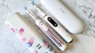 Oral-B Genius X beside Oral-B iO Series 9, both with their travel cases
